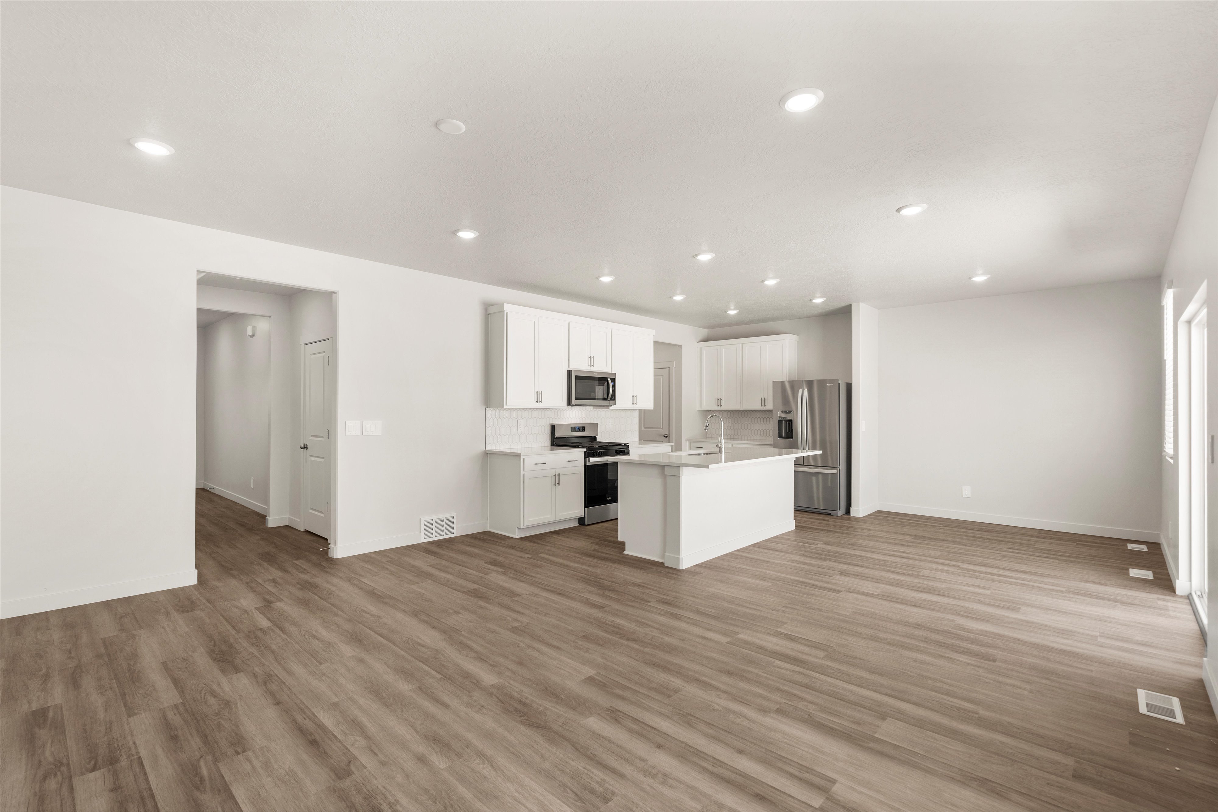 **DISLCAIMER** Exterior & Interior packages may vary.Kitchen with open floor plan, stainless steel appliances, a center island with sink, white cabinetry, and recessed lighting
