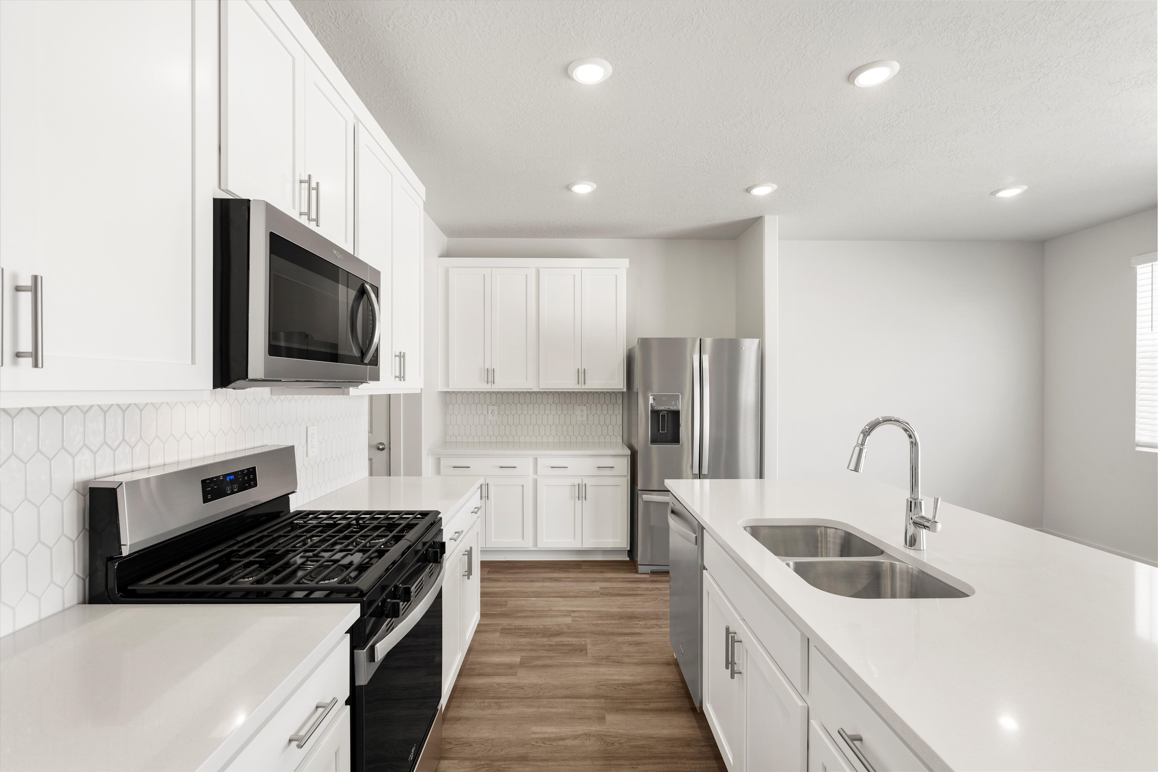 **DISLCAIMER** Exterior & Interior packages may vary.Kitchen with stainless steel appliances, tasteful backsplash, white cabinetry, light stone counters, and recessed lighting