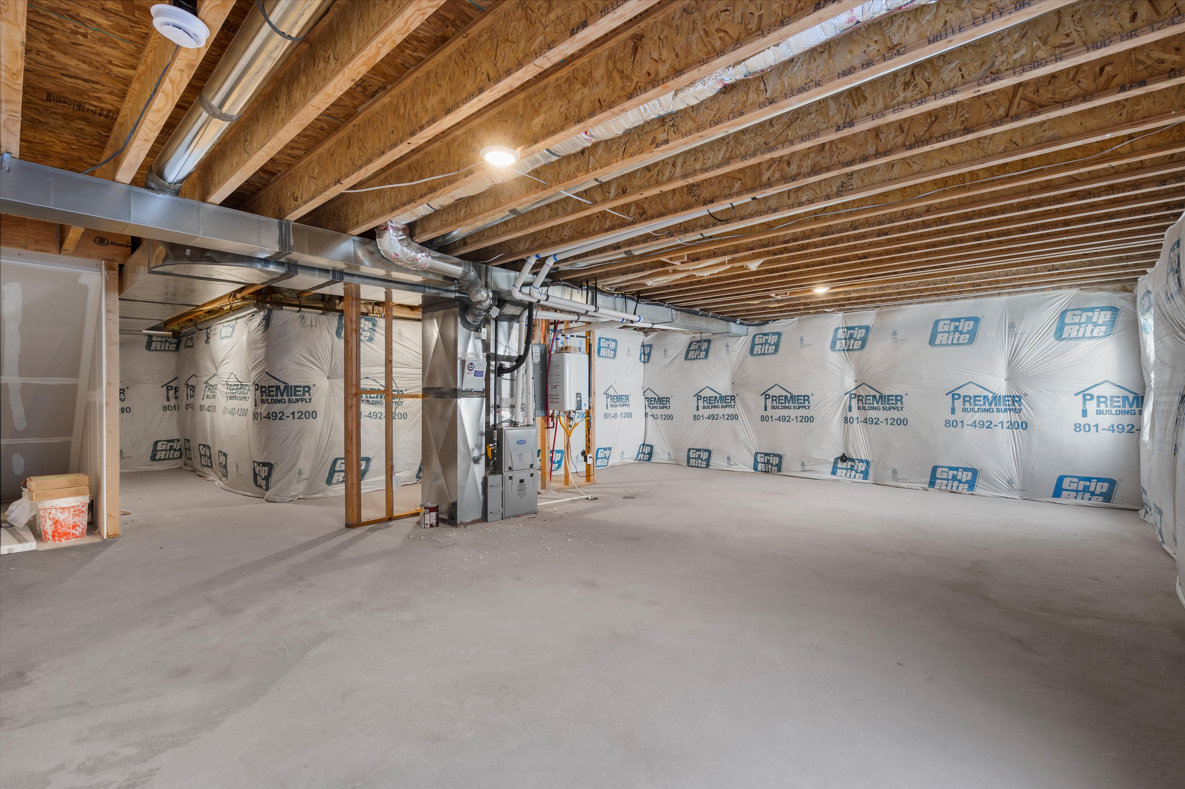 Unfinished basement featuring heating unit and tankless water heater