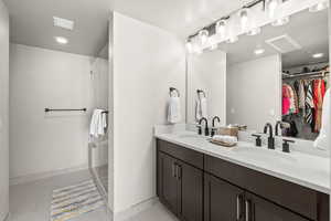 Bathroom featuring double vanity, recessed lighting, a walk in closet, light tile patterned flooring, and a shower stall