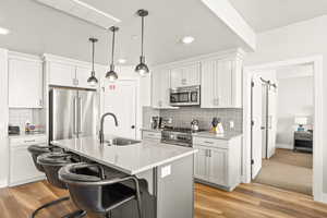 Kitchen featuring a barn door, a breakfast bar area, a center island with sink, white cabinetry, and high end appliances