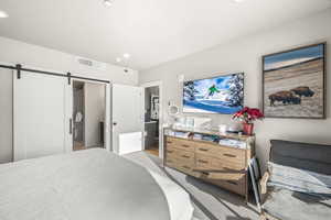 Carpeted bedroom with a barn door and recessed lighting