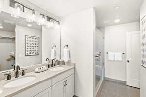Full bath featuring recessed lighting, double vanity, a shower stall, and light tile patterned floors