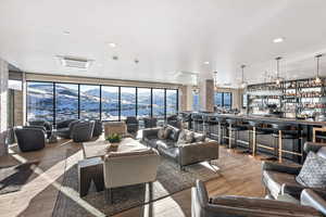 Living area featuring a mountain view, cooling unit, hardwood / wood-style flooring, a wall of windows, and recessed lighting