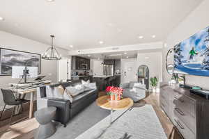 Living room with recessed lighting, light wood-type flooring, and a chandelier