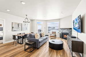Living room featuring a tile fireplace, light wood-type flooring, a chandelier, and recessed lighting