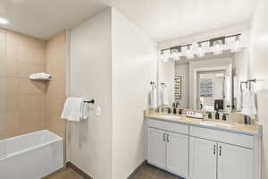 Ensuite bathroom featuring dark tile patterned flooring, double vanity, and bathtub / shower combination