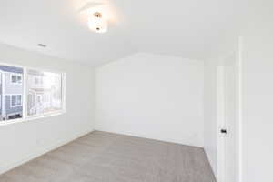 Bonus room with light carpet and vaulted ceiling