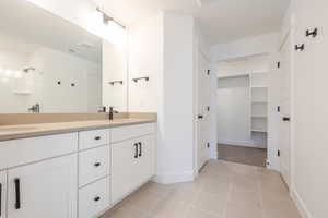 Bathroom featuring double vanity, a shower stall, a walk in closet, and light tile patterned floors