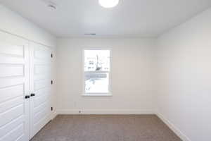 Carpeted spare room with baseboards and a smoke detector