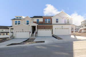 View of front of property featuring board and batten siding, driveway, and an attached garage