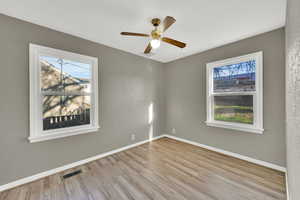Spare room with light wood finished floors, healthy amount of natural light, and ceiling fan