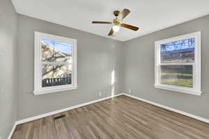 Empty room featuring wood finished floors, healthy amount of natural light, and a ceiling fan