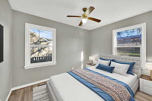 Bedroom with wood finished floors, a ceiling fan, and multiple windows