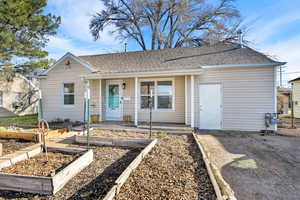 View of front of property with a garden, covered porch, and roof with shingles