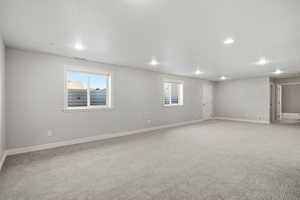 Empty room with light colored carpet, recessed lighting, and a textured ceiling