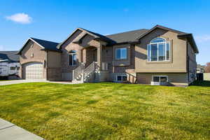 View of front of property with brick siding, a front yard, stucco siding, and driveway