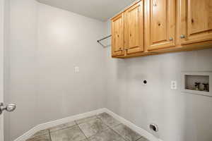 Laundry room with light tile patterned floors, electric dryer hookup, hookup for a washing machine, and cabinet space