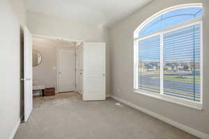 Unfurnished bedroom featuring light colored carpet and baseboards