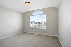 Unfurnished room with vaulted ceiling and light colored carpet
