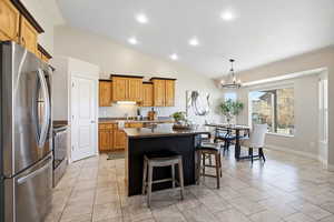Kitchen with stainless steel appliances, a center island, a breakfast bar area, pendant lighting, and a chandelier