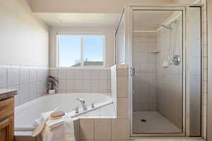 Full bath featuring a bath, a shower stall, and vanity