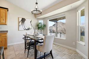 Dining area featuring lofted ceiling, light tile patterned floors, and a chandelier