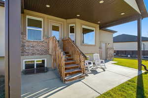Doorway to property featuring a patio area, brick siding, and stucco siding