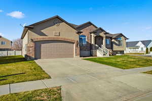 View of front facade with a front yard, driveway, brick siding, and stucco siding