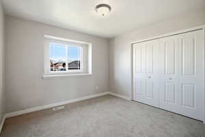 Unfurnished bedroom with light colored carpet and a closet