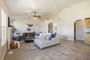 Living room with high vaulted ceiling, a ceiling fan, and arched walkways