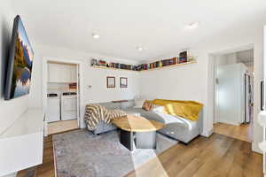 Bedroom with wood finished floors, washer and clothes dryer, freestanding refrigerator, and recessed lighting