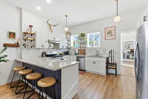 Kitchen with open shelves, light stone countertops, hanging light fixtures, a peninsula, and recessed lighting