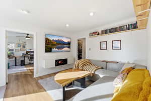 Living area with an office area, wood finished floors, a glass covered fireplace, and recessed lighting