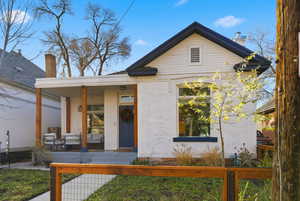 View of front of house with brick siding, a porch, a fenced front yard, and a chimney