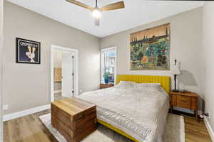 Bedroom with wood finished floors, connected bathroom, and ceiling fan