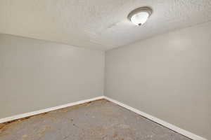 Empty room with unfinished concrete flooring and a textured ceiling