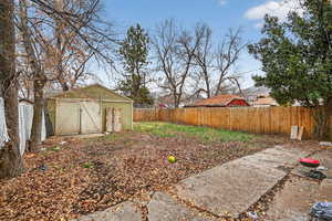 Fenced backyard featuring a storage unit