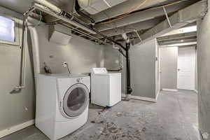 Laundry room featuring washing machine and clothes dryer, concrete flooring, and a textured wall