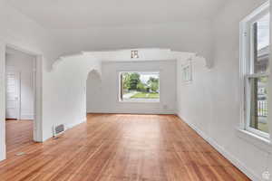 Unfurnished room with arched walkways and light wood finished floors