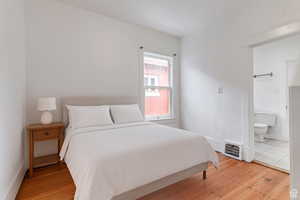 Bedroom with light wood-style floors and ensuite bathroom