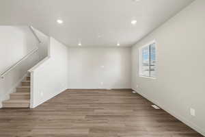 Unfurnished living room with light wood-style flooring, stairway, and recessed lighting