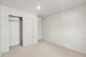 Unfurnished bedroom featuring light colored carpet and a closet