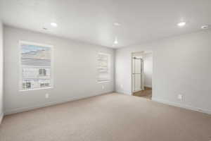 Unfurnished room with light carpet, healthy amount of natural light, recessed lighting, and a textured ceiling