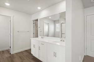Bathroom with double vanity, dark wood-type flooring, recessed lighting, and a stall shower