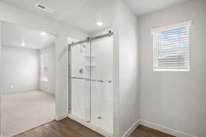 Bathroom with dark wood-style floors and a shower stall