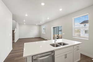 Kitchen featuring white cabinets, a center island with sink, dishwasher, dark wood-type flooring, and recessed lighting