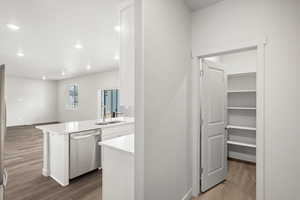 Kitchen with light wood-style flooring, recessed lighting, dishwasher, white cabinets, and a peninsula