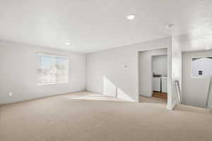 Unfurnished room with washing machine and clothes dryer, carpet, a textured ceiling, and recessed lighting