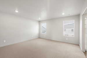 Empty room with light colored carpet, recessed lighting, and a textured ceiling